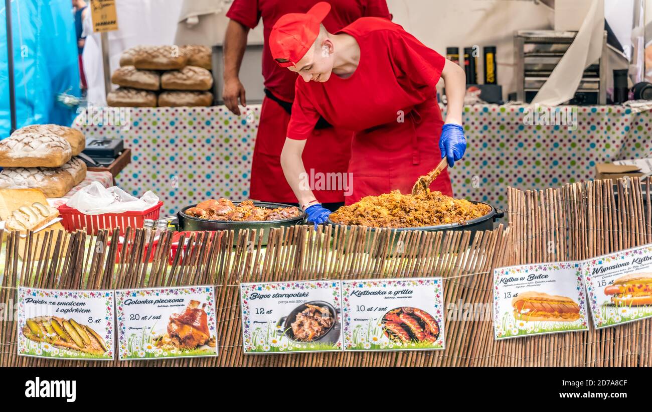Stettin, Polen Jun 2019 Junge Köchin kocht ein traditionelles polnisches Essen namens Bigos in großer Pfanne auf dem Straßenmarkt oder fair. Tage des Meeres, Stettin Stockfoto