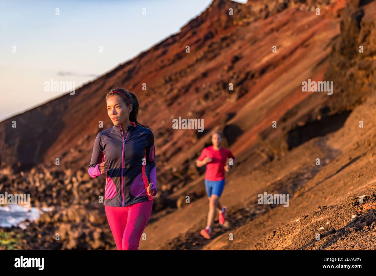 Gemeinsam trainieren sportliche Paare in der Outdoor-Berglandschaft. Asiatische Läuferin Frau läuft auf Trail-Pfad mit Mann im Hintergrund. Sportler Stockfoto