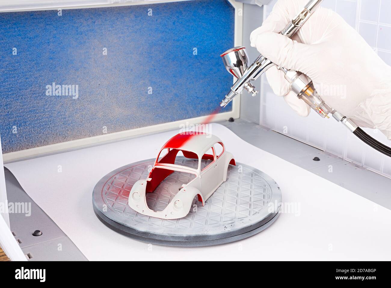Lackierung mit Metall Chrom Airbrush Spray Spritzpistole auf roten Retro-Maßstab Modell Retro Oldtimer in Lackierkabine. Hobby Industrie Konzept Hintergrund Stockfoto