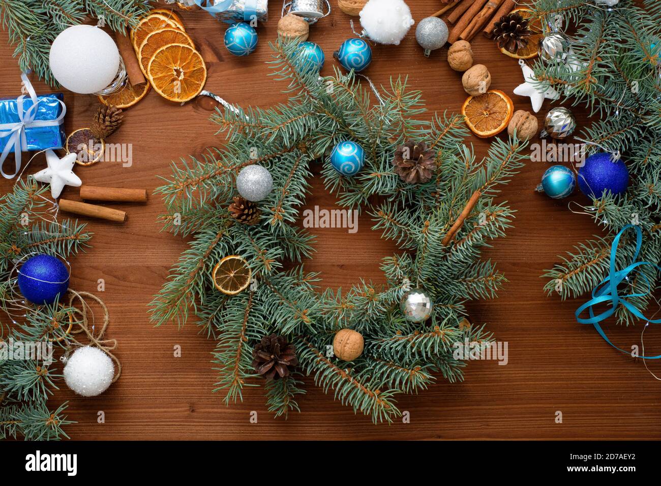 Schritt-für-Schritt-Prozess der Herstellung eines Weihnachtsbaumkranz zu Hause aus Fichtenzweigen, Orangen und Weihnachtskugeln in den silbernen und blauen Farben der Stockfoto