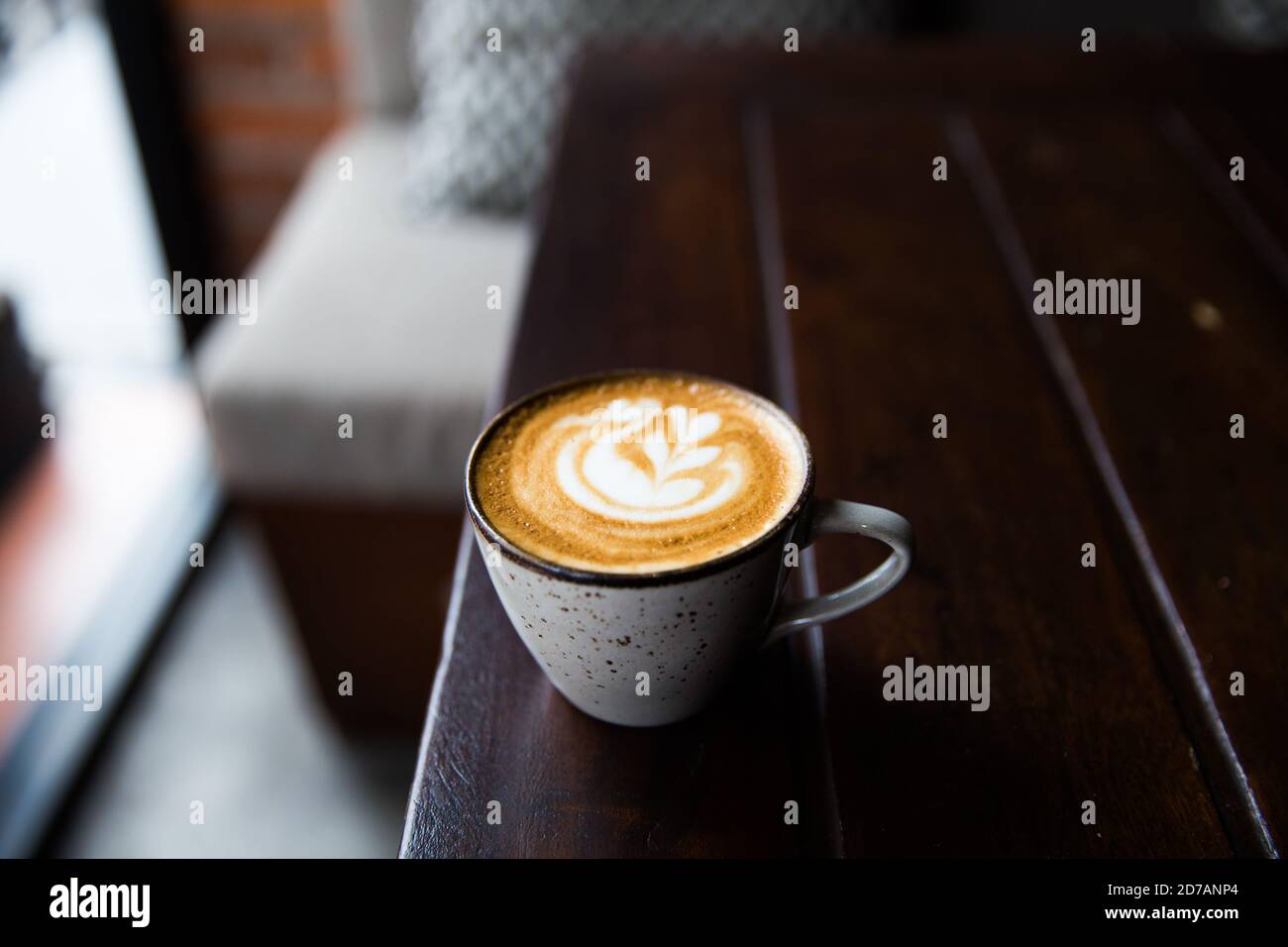 Graue Tasse heißen Cappuccino auf dunklem Holzschreibtisch Hintergrund. Frühstückszeit. Stockfoto