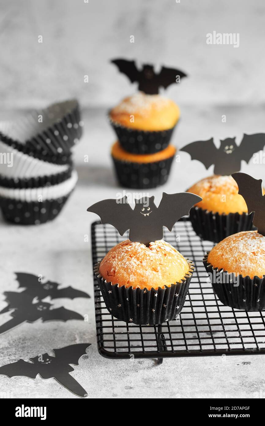 Halloween Kürbis Muffins in schwarzen Kapseln mit Karton Fledermäuse verziert. Festliche Halloween Cupcakes. Nahaufnahme des köstlichen gruseligen halloween Muf Stockfoto