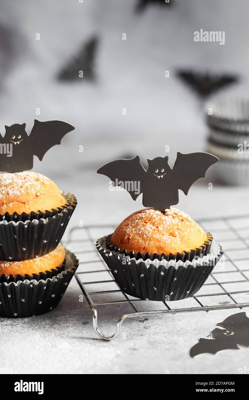 Halloween Kürbis Muffins in schwarzen Kapseln mit Karton Fledermäuse verziert. Festliche Halloween Cupcakes. Nahaufnahme des köstlichen gruseligen halloween Muf Stockfoto