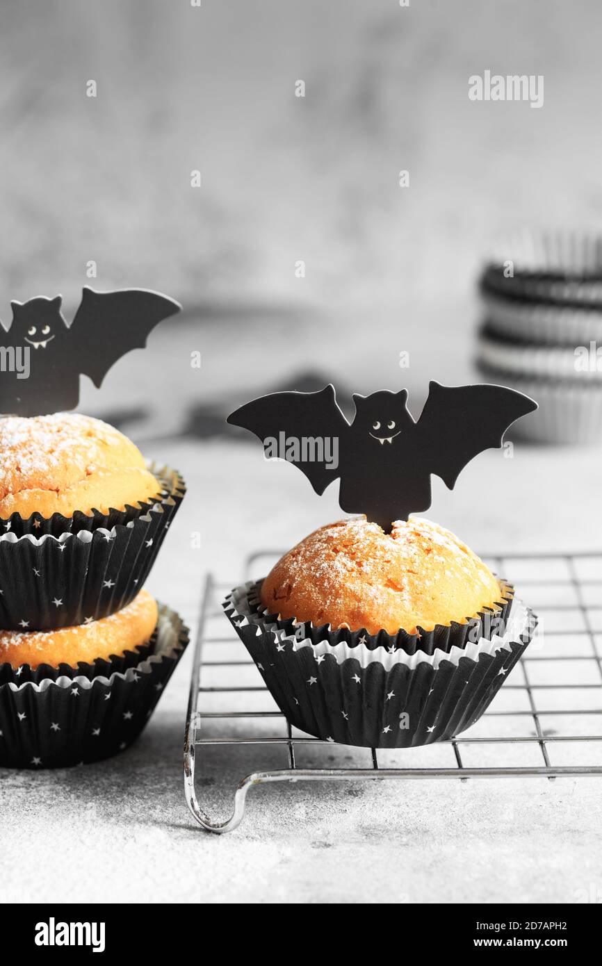 Halloween Kürbis Muffins in schwarzen Kapseln mit Karton Fledermäuse verziert. Festliche Halloween Cupcakes. Nahaufnahme des köstlichen gruseligen halloween Muf Stockfoto