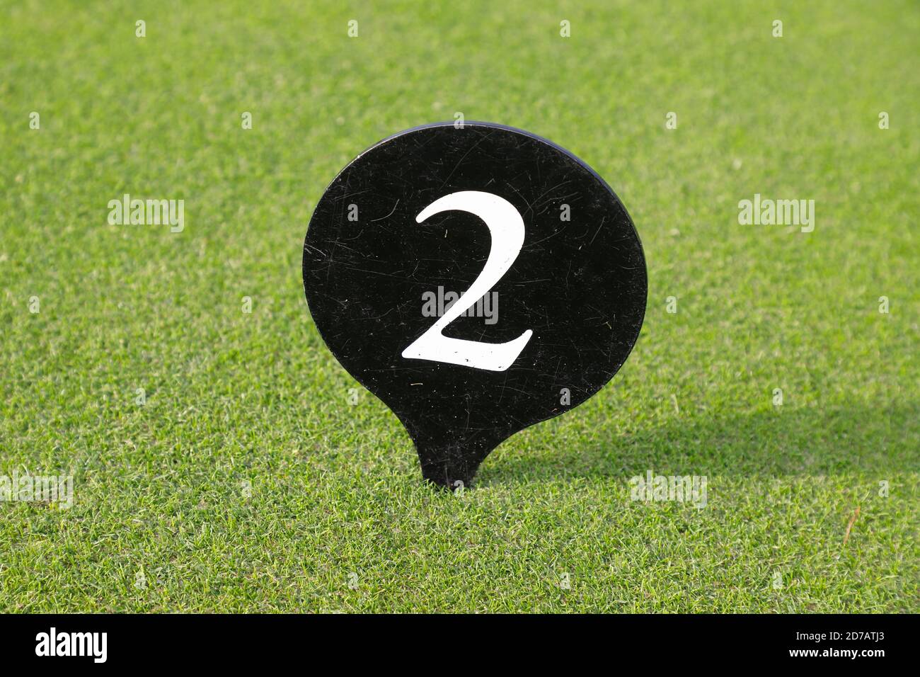 Weiße Zahl zwei auf einem schwarzen Teller vor einem grünen Rasen Hintergrund. Stockfoto