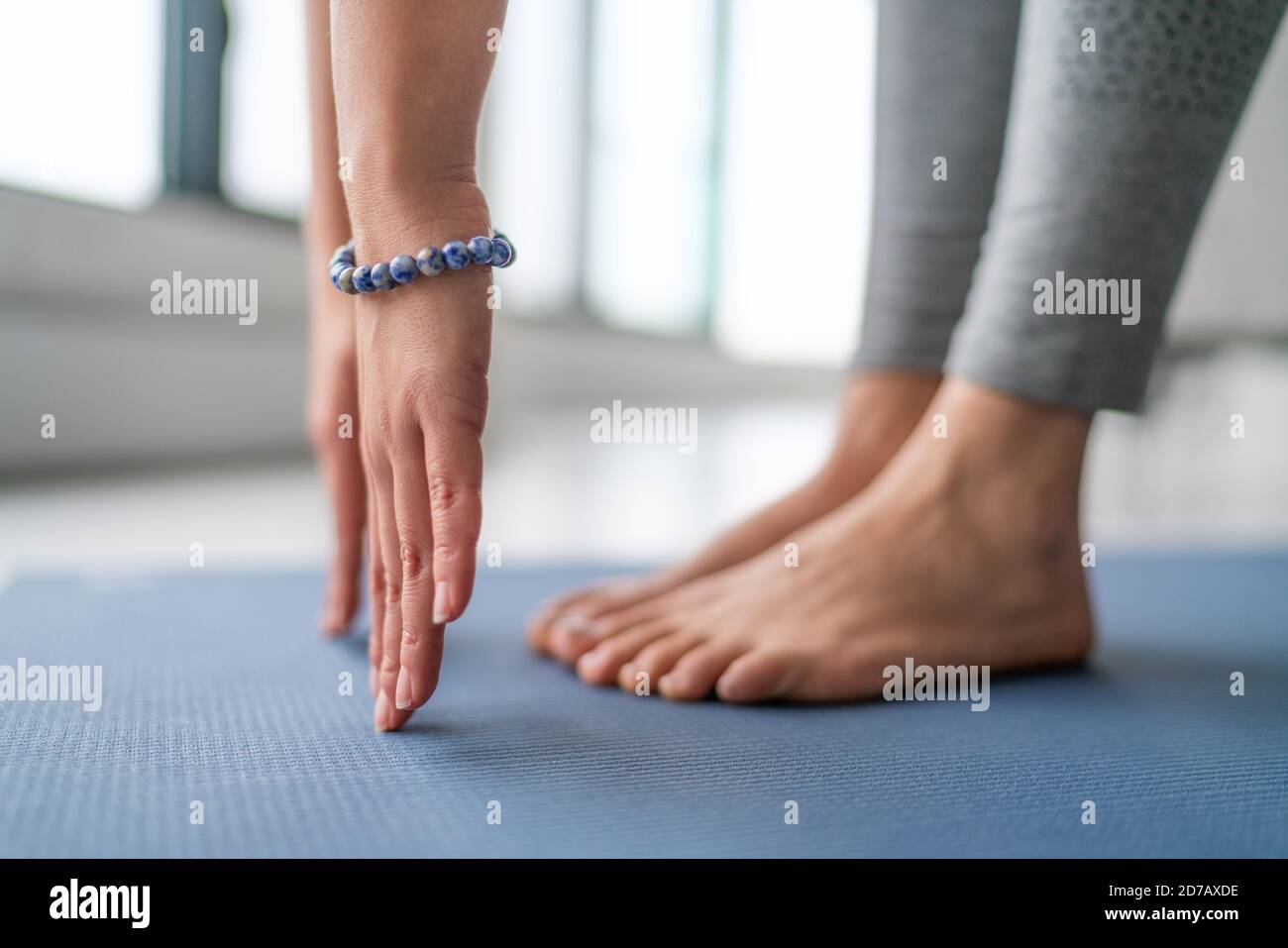Yoga im Fitness Studio - Yogi Lehrer Stretching in vinyasa Yoga-Klasse. Nahaufnahme der Hände mit blauem Armband und Füßen Stockfoto