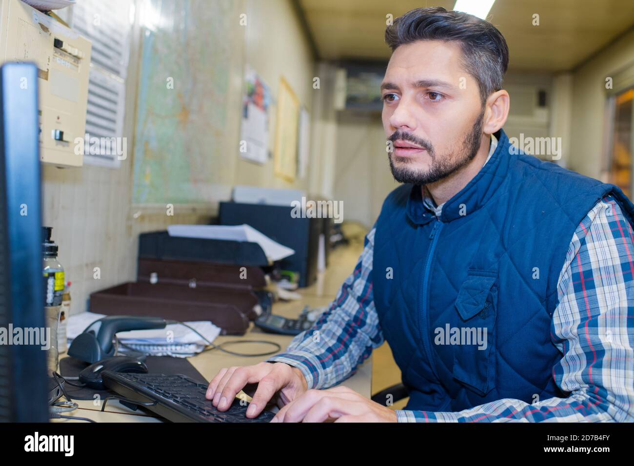 Mann am Computer im Lagerbüro vor Ort Stockfoto