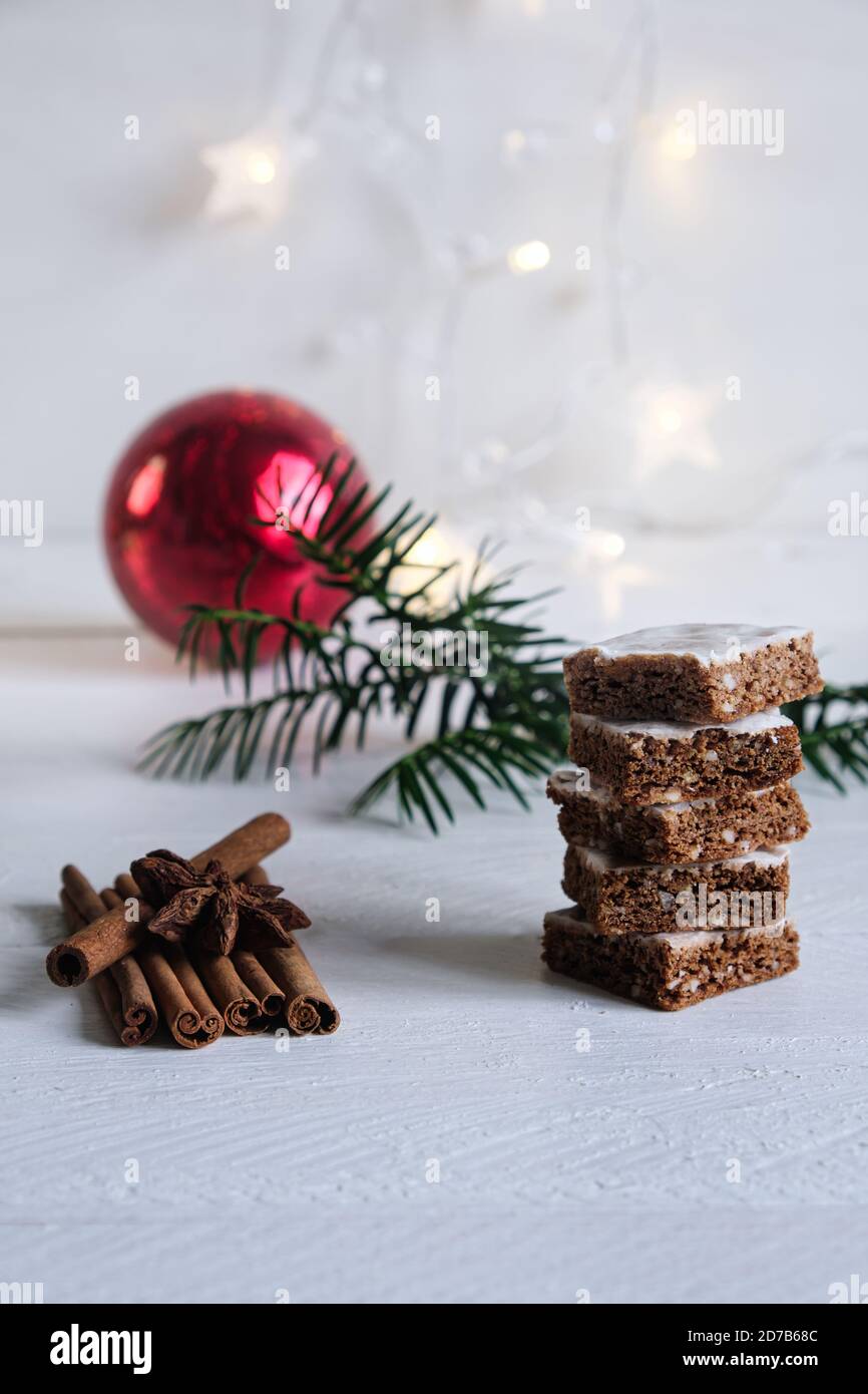 Advent- und Weihnachtsstimmung, Honigkuchen gestapelt, auf einem weißen Holztisch im Hintergrund ein Tannenzweig und eine rote Weihnachtskugel Stockfoto