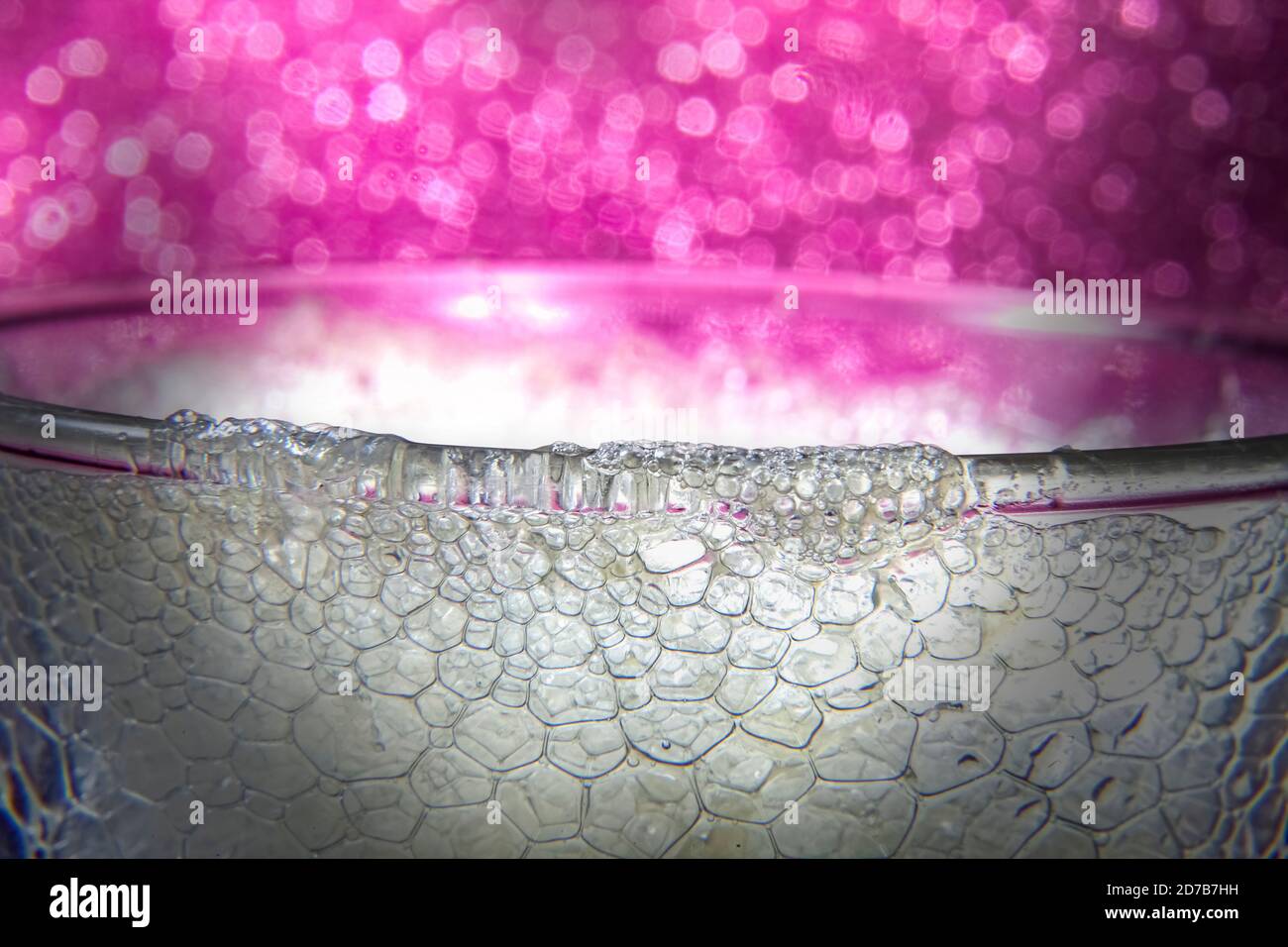 Soda-Effekt von Zitronenschaum, der auf Glasrand ausgießt Auf rosa Bokeh Hintergrund Stockfoto