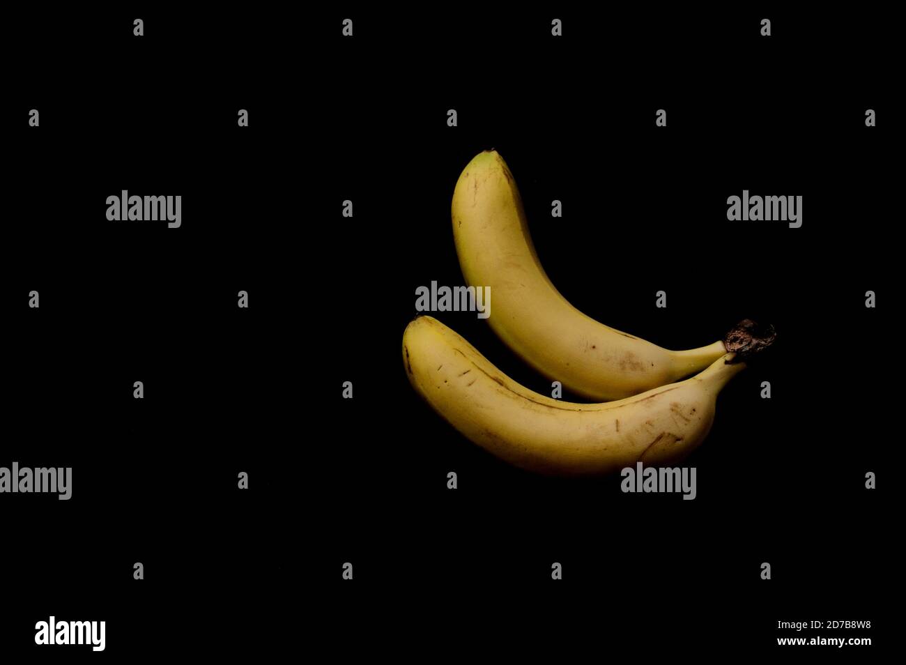 Nahaufnahme einer Hand gelber Bananen isoliert auf schwarzem Hintergrund, mit Kopierraum Stockfoto