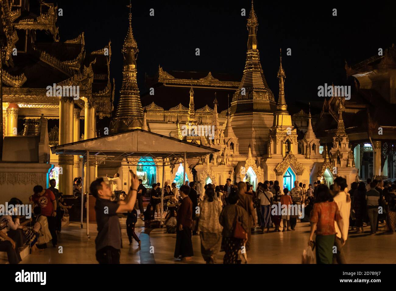 Yangon, Myanmar - 30. Dezember 2019: Die Menschen besuchen die Shwedagon Pagode und ihre umliegenden goldenen Strukturen während des dunklen Abends Stockfoto