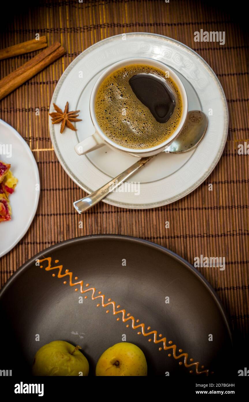 Stillleben - eine heiße Tasse schwarzen Kaffee, hausgemachte Kekse mit Obst, gebackene Äpfel auf einer Bambusmatte Stockfoto