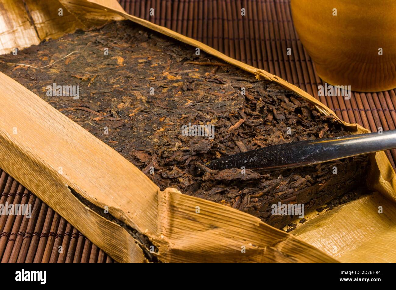 Chinesisch gepressten PU-erh Tee in Bambus Blatt Verpackung und Teemesser  auf einem Bambus-Matte, close-up, Makro Stockfotografie - Alamy