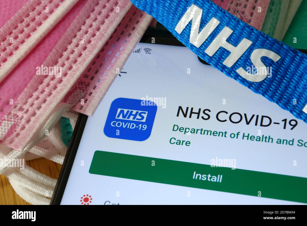Manchester / Großbritannien - 17. Oktober 2020: NHS COVID-19 App im Play Store auf dem Bildschirm des Smartphones neben viralen Masken und NHS Lanyard zu sehen. Stockfoto