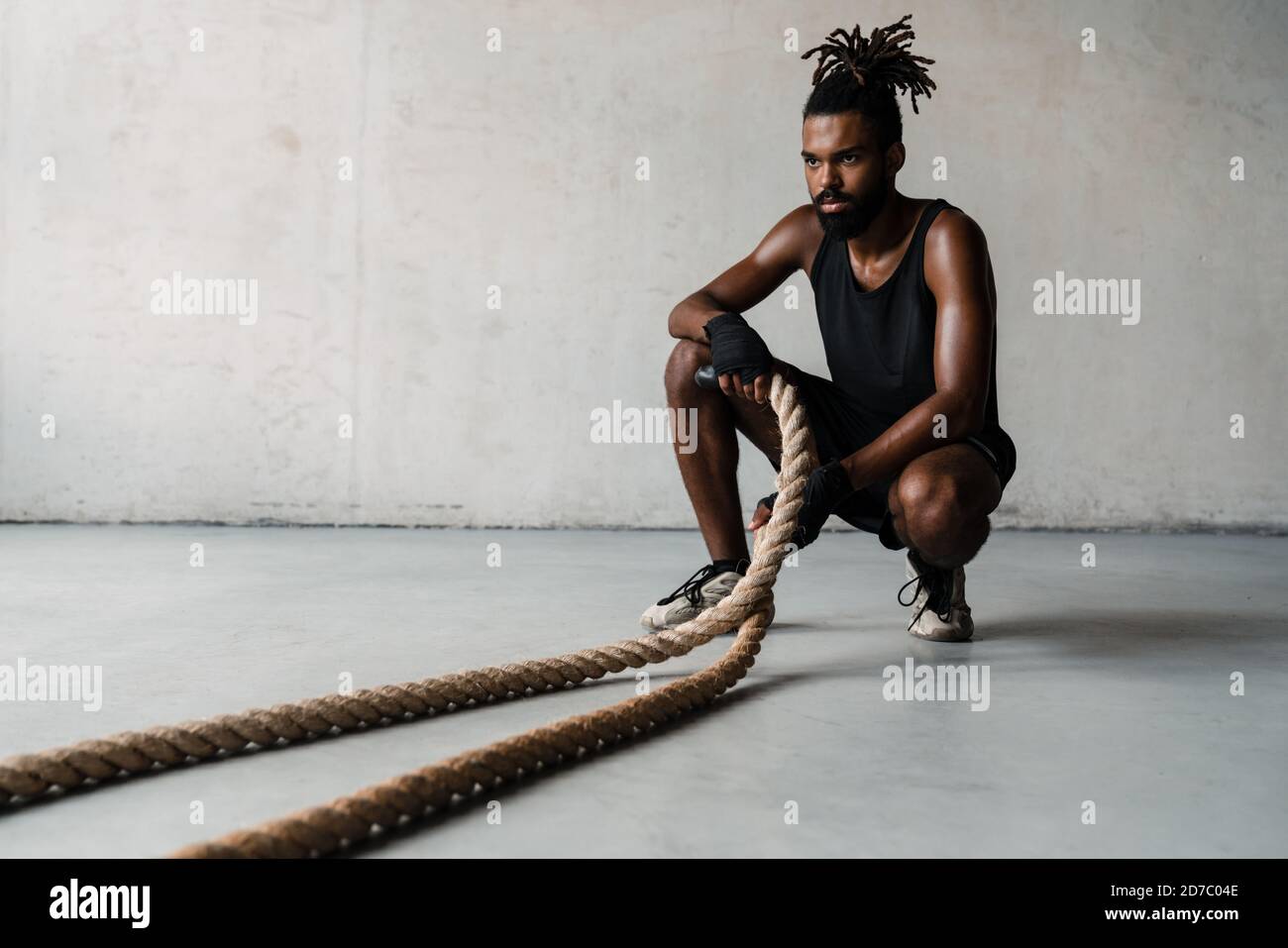 Bild des athletischen afroamerikanischen Sportlers, der mit Kampf ausarbeitet Seile im Innenbereich Stockfoto