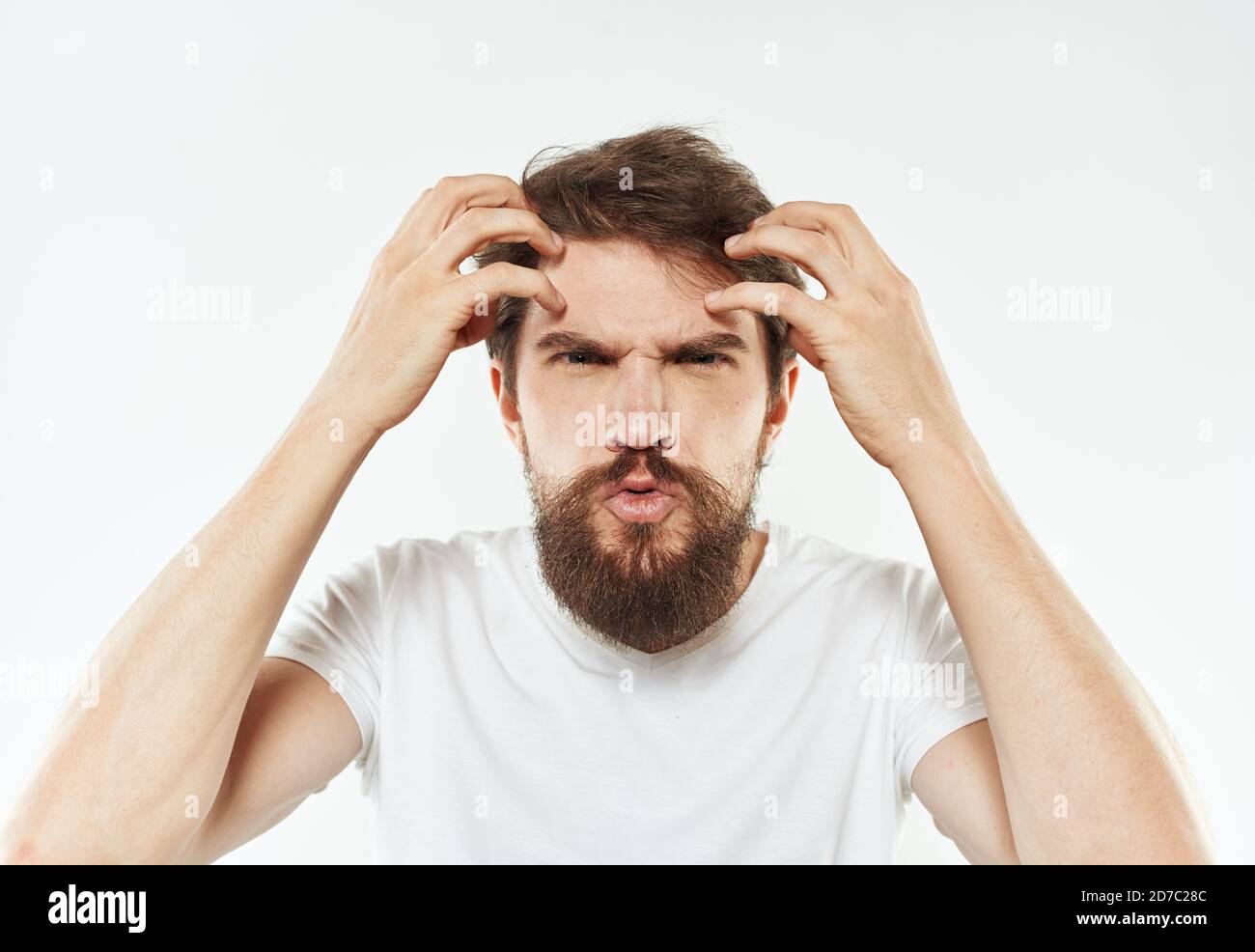 Ein junger Mann in einem weißen T-Shirt stünket mit seinem Hände Emotionen Reizbarkeit Stress Stockfoto