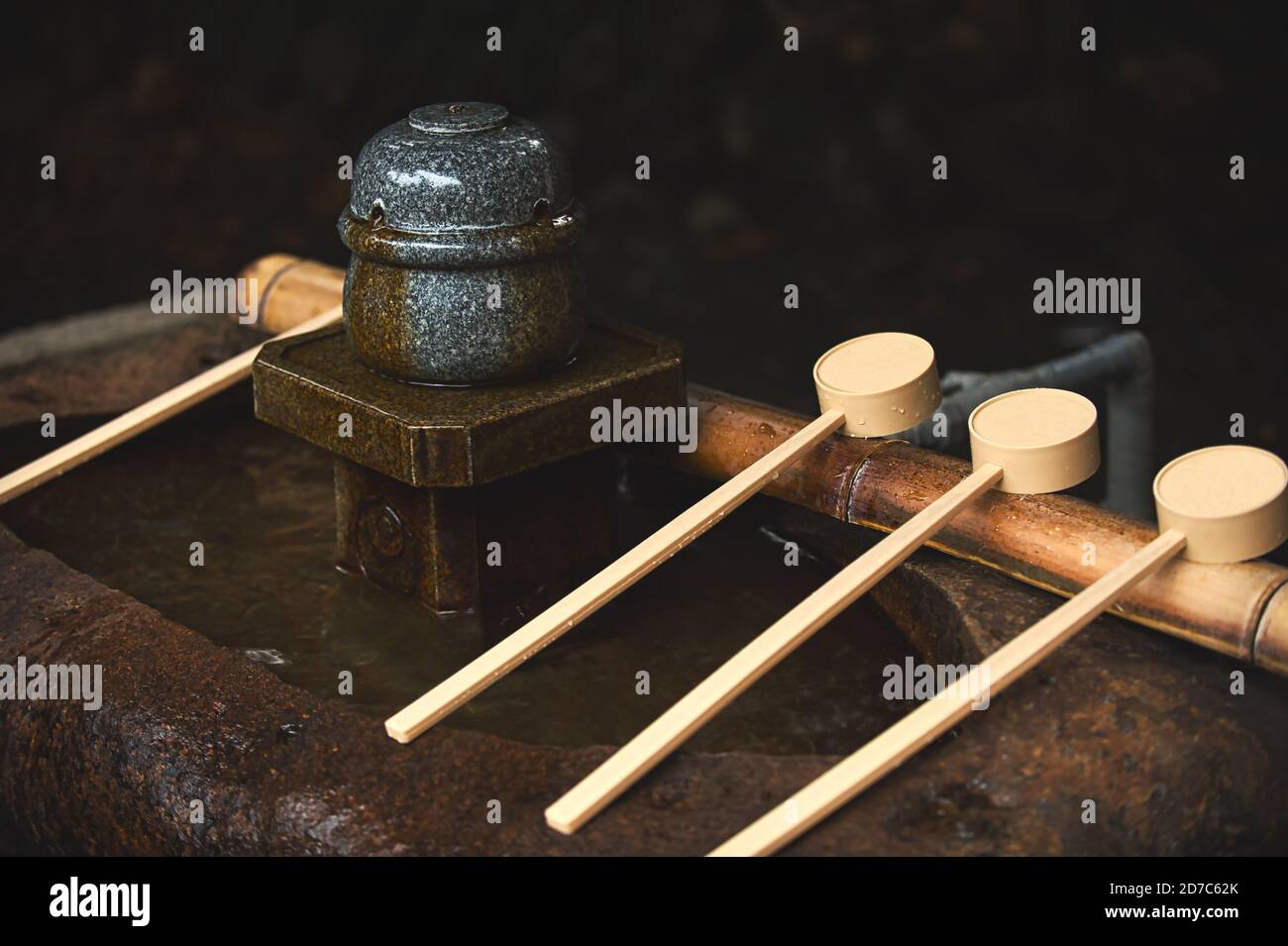 Hölzerne Schöpfkelle auf einem Bambusstock auf einem Steinbecken platziert, verwendet Chozuya Wasser, um seine Hände zu waschen, bevor er in einen Shinto-Tempel in Japan ging. Im e platziert Stockfoto