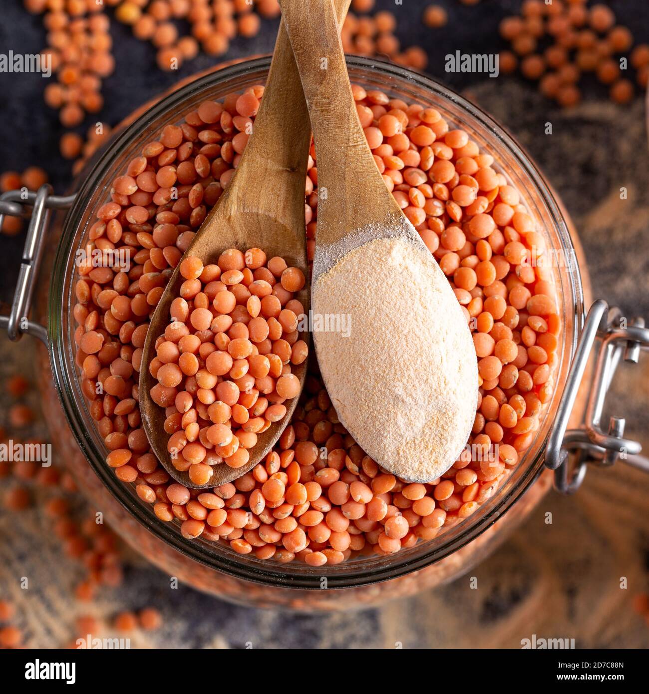 Rote Linsen und Linsenmehl in den Holzlöffeln über einer Schüssel rote Linsen. Stockfoto