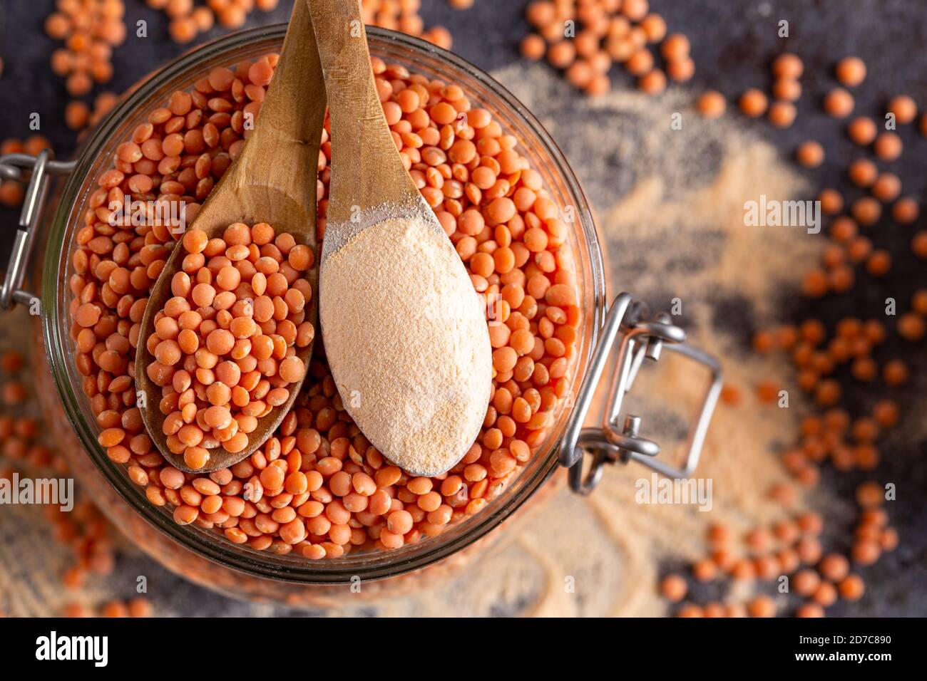Rote Linsen und Linsenmehl in den Holzlöffeln über einer Schüssel rote Linsen. Stockfoto