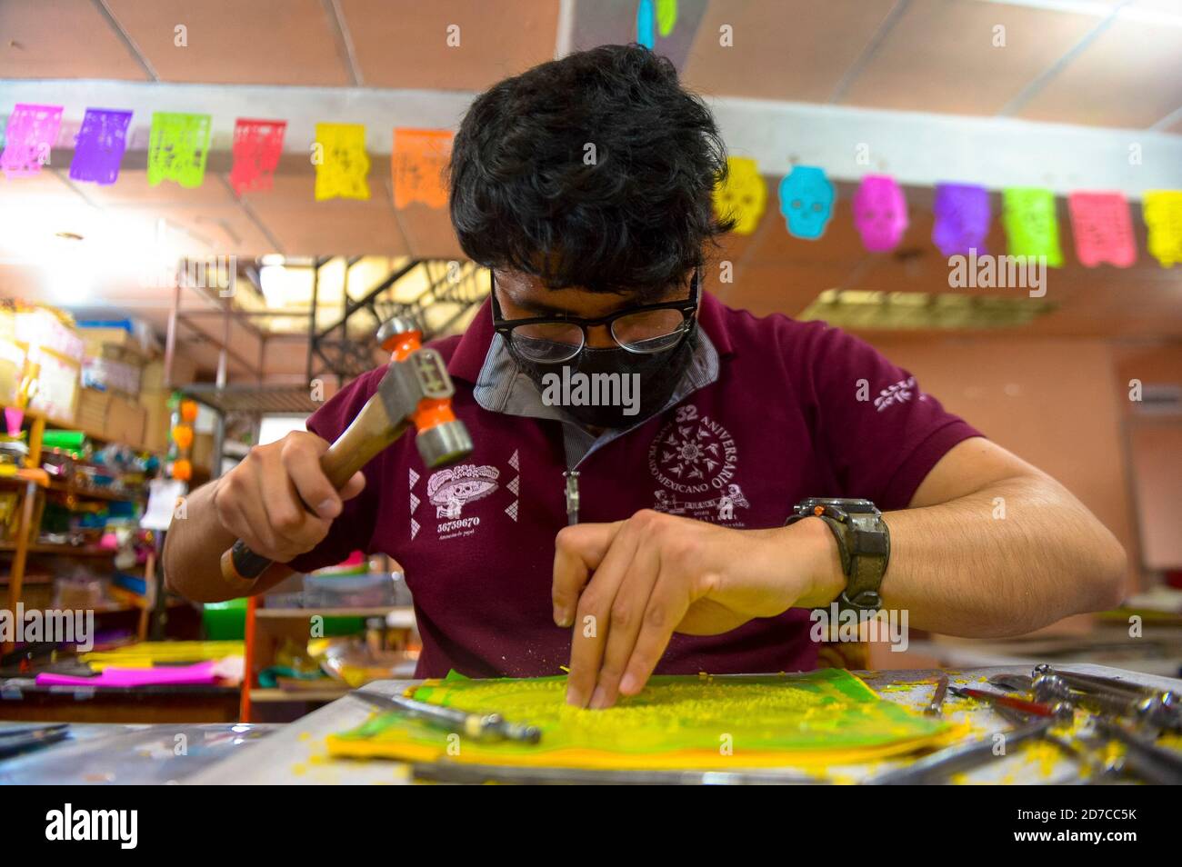 MEXIKO-STADT, MEXIKO - OKTOBER 21: Ein Arbeiter aus der "Taller de Yuriria" trägt eine Schutzmaske, während er eine Schablone verwendet, um ein traditionelles mexikanisches Papier "Papel Picado" zu schneiden, das verwendet wird, um Opfergaben und die Straßen der Stadt während der Tag der Toten (Dia de Muertos) Feiern zu schmücken. Am 21. Oktober 2020 in Mexiko-Stadt, Mexiko. Taller Yurita gegründet seit 32 Jahren von Alberto Torres im Jahr 1988. Der erlernte den Handel in einer autodidaktischen Weise, um die Technik von Papel Picado zu perfektionieren. Quelle: The Photo Access/Alamy Live News Stockfoto