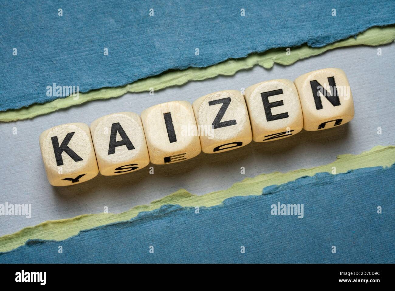 kaizen Wortabstrakt in Holzbuchstabenwürfeln gegen Papier abstrakt in Grüntönen, Japanisch kontinuierliche Verbesserung und eine Änderung für besseres Konzept Stockfoto
