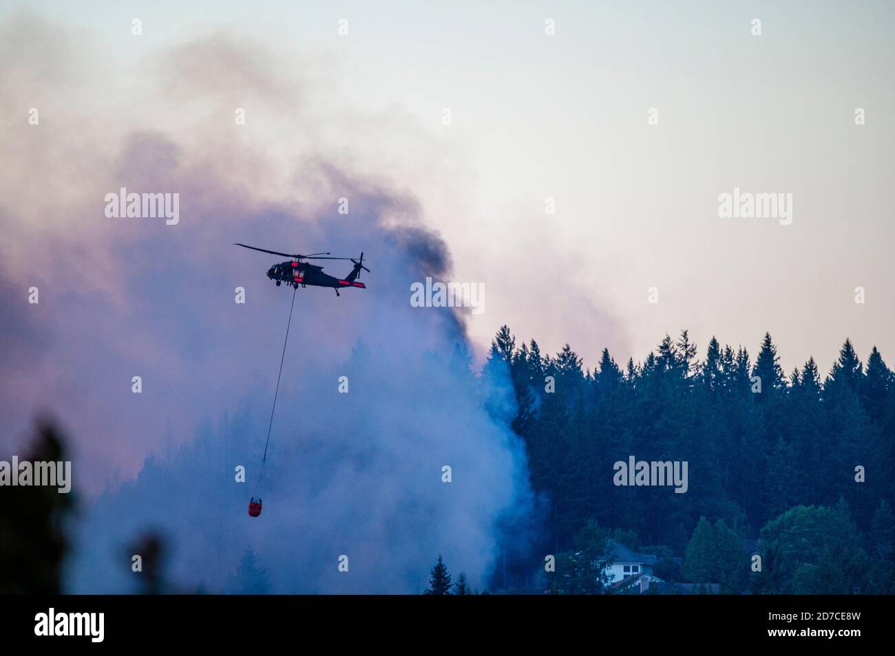 Aerial Brandbekämpfung Hubschrauber mit Feuereimer fliegen in Rauch zu Lassen Sie Wasser auf dem Lauffeuer fallen Stockfoto