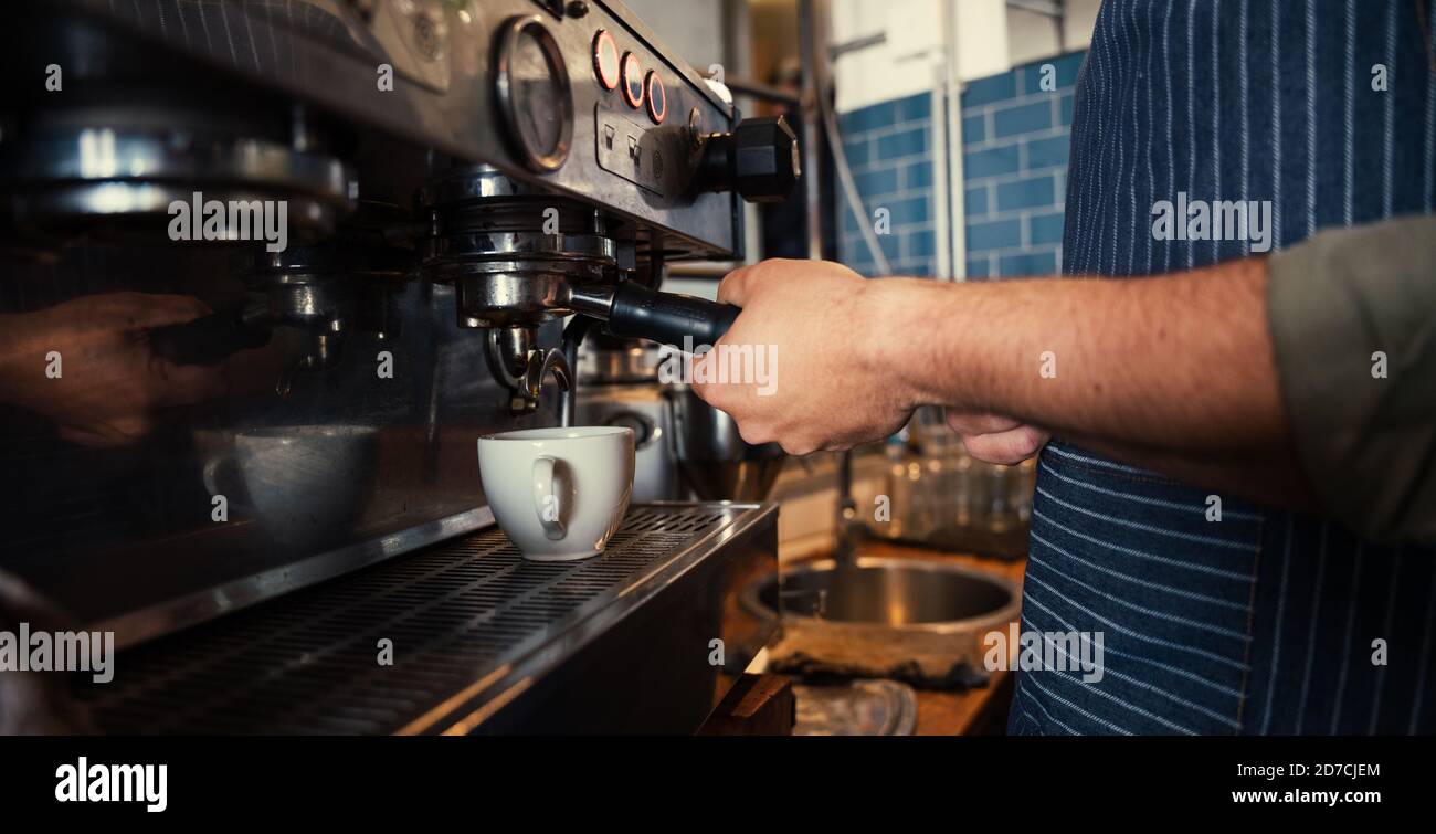 Männlicher Barista, der Kaffee für die Gäste in einem funky Restaurant zubereitet Stockfoto