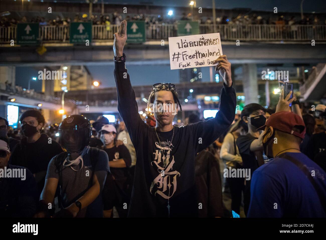 (ANMERKUNG DES HERAUSGEBERS: Bild enthält Obszönität) EIN prodemokratischer Protestler hält ein Plakat mit der Aufschrift '#FreeThailand', während er während einer regierungsfeindlichen Demonstration in der thailändischen Hauptstadt den dreifingigen Gruß überreicht. Tausende von prodemokratischen Demonstranten gingen ‘sSiegessäule auf die Straße und forderten den Rücktritt des thailändischen Premierministers und die Reform der Monarchie am siebten Tag nach einem „beharrlichen Ausnahmezustand“, den Premierminister Prayut Chan-o-cha ausgerufen hatte. Die Demonstranten marschierten vom Siegessäule zum Regierungsgebäude und übergaben Premierminister Prayut Chan-o-cha einen Brief, in dem sie ihn fragten Stockfoto