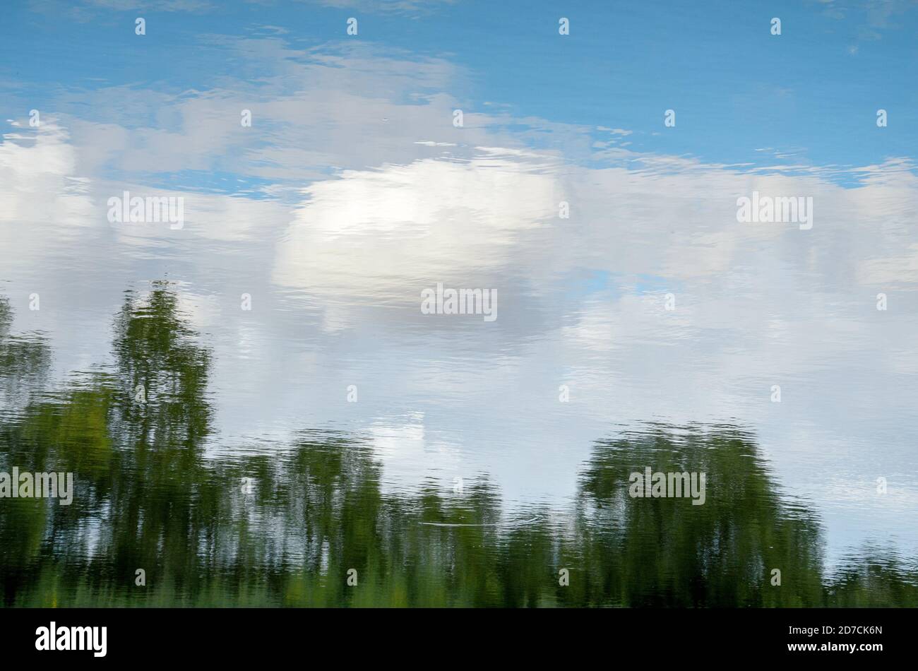 Abstrakter Sommer Natur Landschaft.Blauer Himmel mit weißen Wolken und Bäumen auf Wasseroberfläche reflektiert. Stockfoto