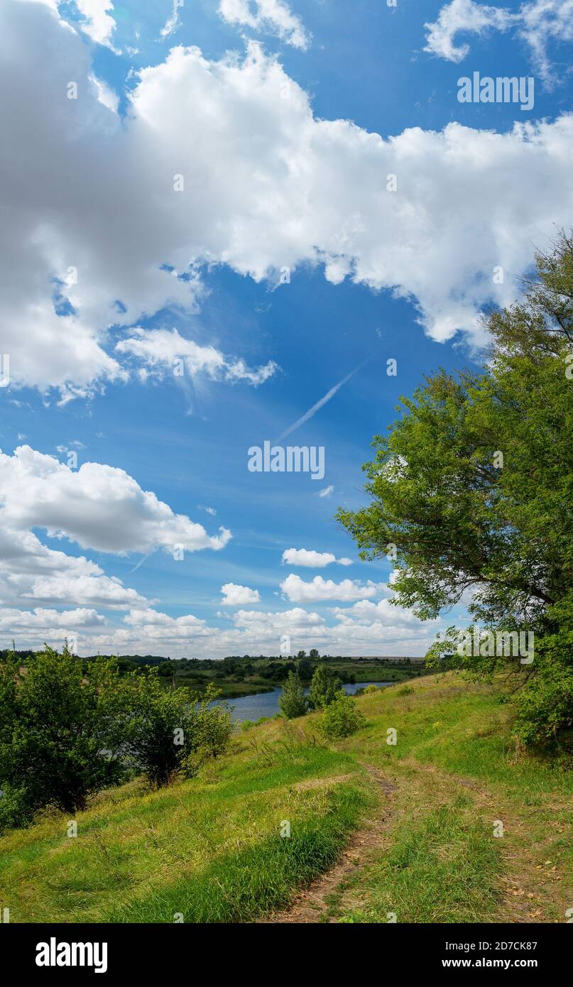 Sonnige ländliche russische Landschaft mit Landstraße, Fluss und grünen Feldern Stockfoto
