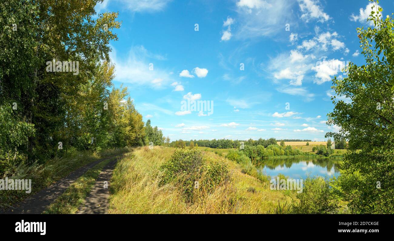 Sonnige Sommer ländliche Landschaft mit ruhigen Fluss, Landstraße und golden Farmfelder Stockfoto