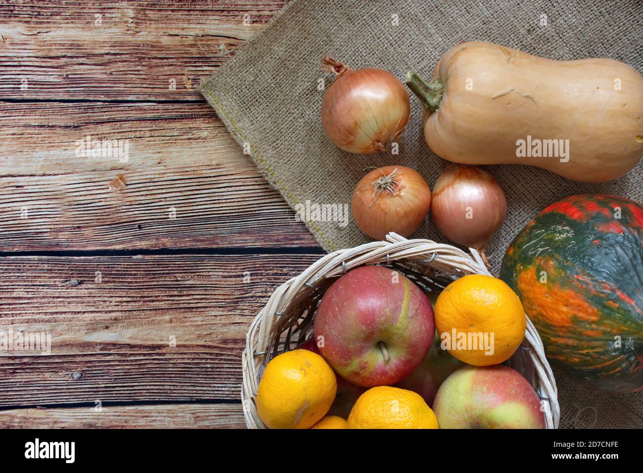 Herbstkomposition mit Kürbis, Zwiebel, Apfel und Mandarine auf Holzgrund Stockfoto