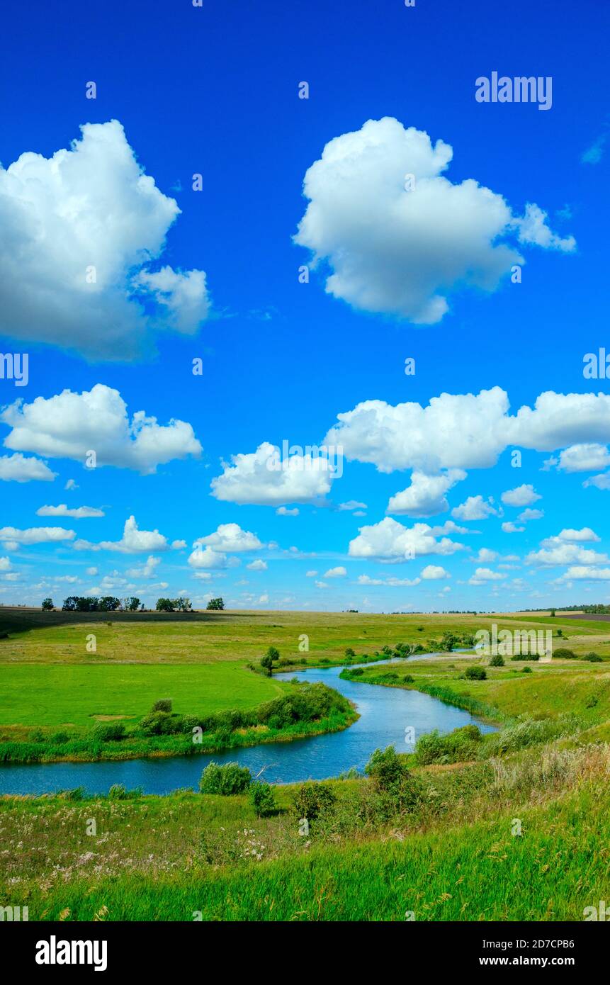 Sonnige Sommerlandschaft mit Fluss, grünen Hügeln und schönen Wolken in blauem Himmel. Stockfoto