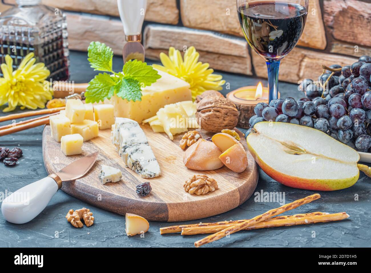 Käseplatte aus verschiedenen Käsesorten - Emmentaler, hausgemachte, Parmesan, Blauschimmelkäse, Brotscheiben, Walnüsse, Rosinen, Birne, Trauben, Glas Wein auf Stockfoto