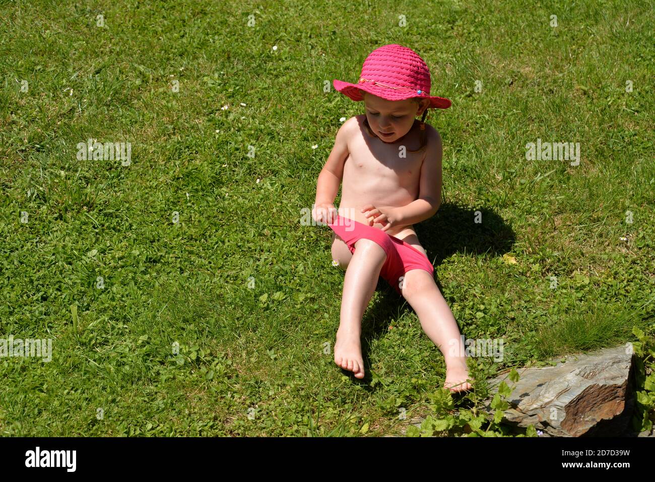 Nass kleines Mädchen nach dem Spielen mit dem Wasserstrahl in Badeanzug Stockfoto