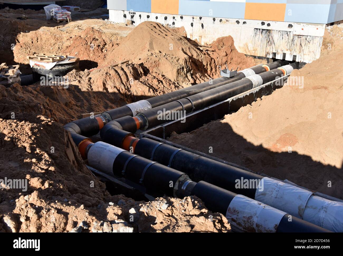 Verlegung von Heizrohren in einem Graben auf der Baustelle. Installation von unterirdischen Sturmsystemen für die Wasserleitung und die Sanitärabwasserkanäle Kaltes und warmes Wasser, Heizung Stockfoto