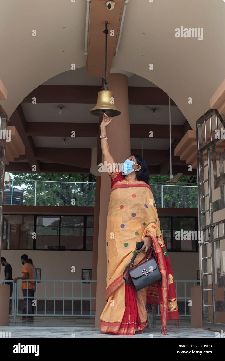 Eine hinduistische Anhängerin mit Gesichtsmasken wird während des Durga Puja Festivals in Dhaka die Glocke läuten sehen.Gesundheitsbeamte haben vor dem Potenzial gewarnt, dass sich das Coronavirus während der kommenden religiösen Festsaison, die von riesigen Versammlungen in Tempeln gekennzeichnet ist, ausbreiten kann. Stockfoto