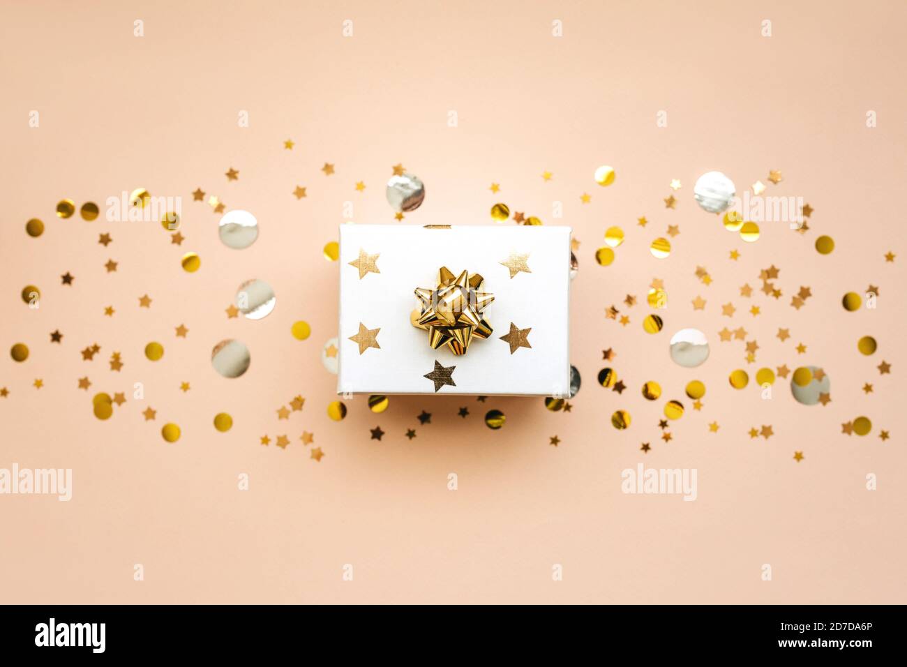 Box mit einem Geschenk auf einem rosa Hintergrund mit goldenen und silbernen Konfetti. Festlicher Hintergrund. Stockfoto