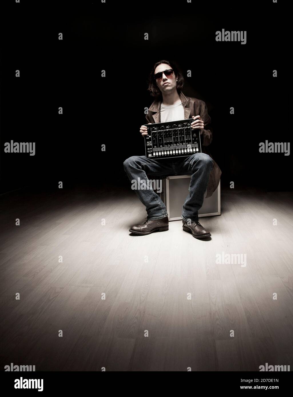 Hip-Hop-Musikerportrait mit Beat-Maschine und dunklem Studiobeleuchtung. Stockfoto
