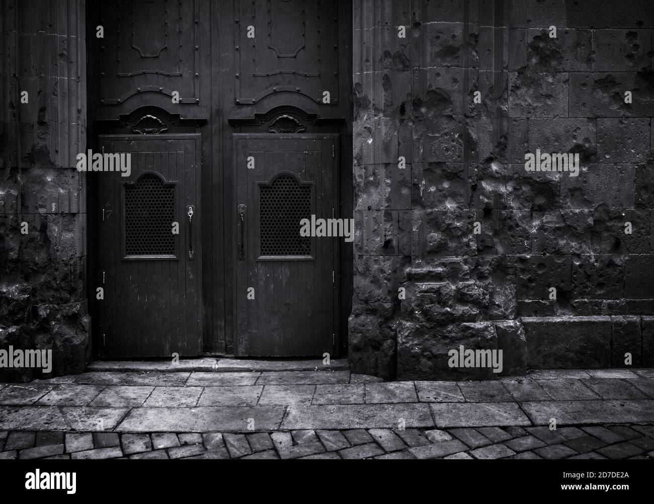 Schwarz-Weiß-Bild dunkel Edition.Schrapnel Aufprall gegen eine Wand Und alten Tempel Tür Saint Philip Neri in Barcelona Spanien Stockfoto