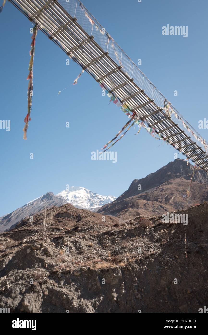 Nepal. Hängebrücke mit buddhistischen Fahnen über dem Fluss in Annapurna Circuit. Stockfoto