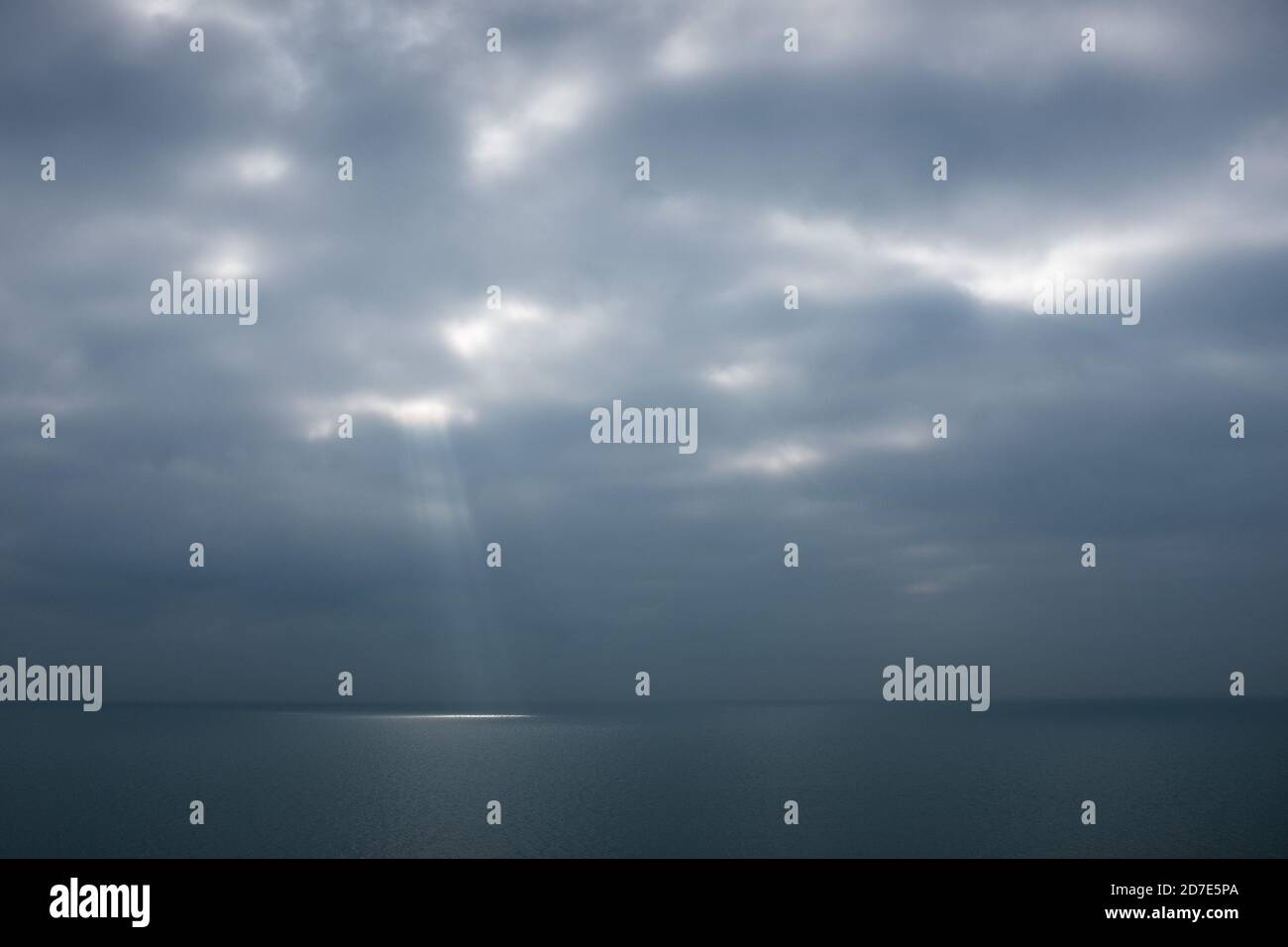 Ein Lichtschacht bricht durch die Wolken und beleuchtet an einem langweiligen Februartag einen kleinen Fleck des Ärmelkanals am Strand von Boscombe in Bournemouth. 10. Februar 2015. Foto: Neil Turner Stockfoto