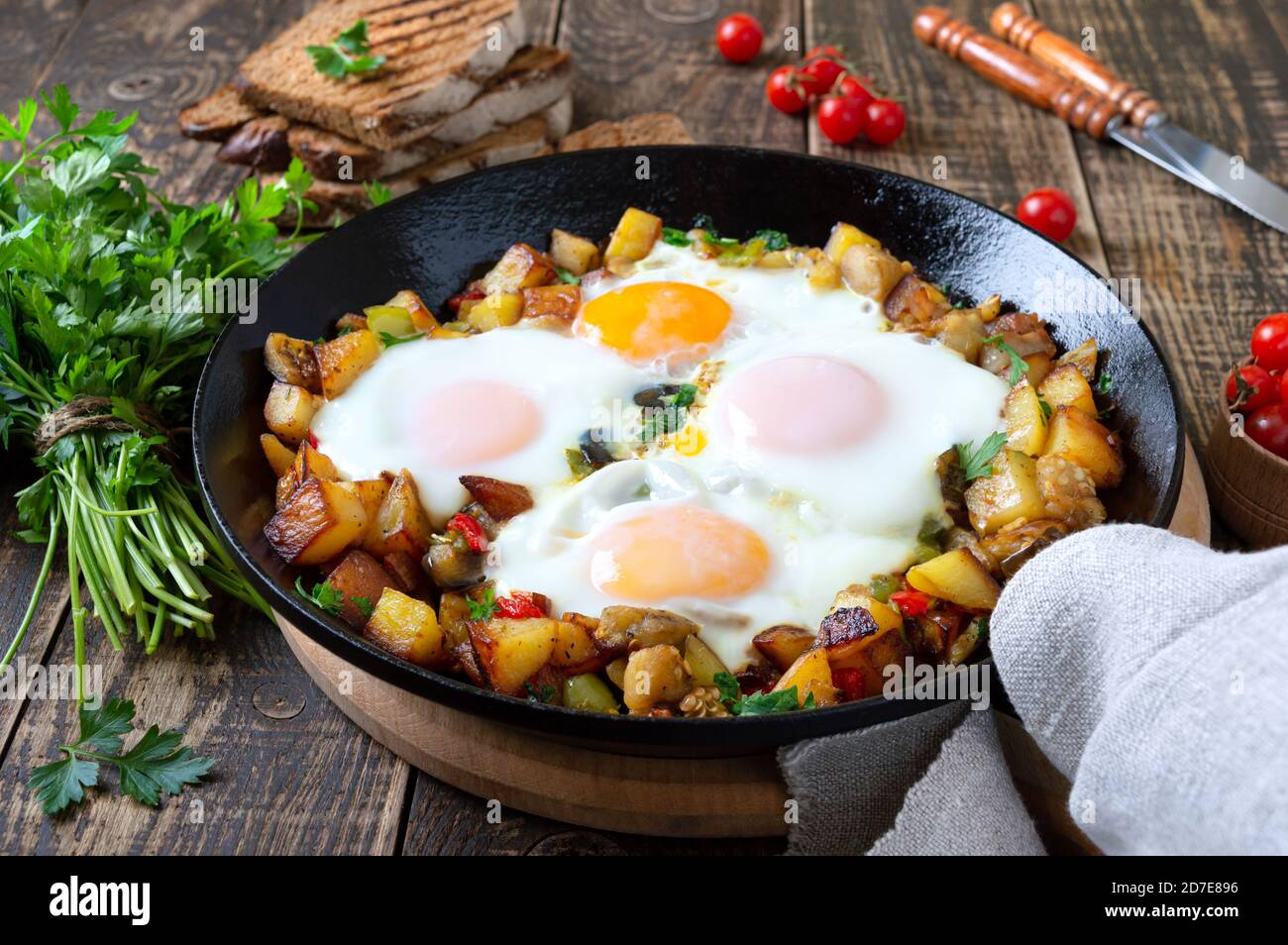 Spiegeleier mit Gemüse - shakshuka in der Pfanne und Roggenbrot auf einem alten hölzernen Hintergrund. Spätes Frühstück. Rustikaler Stil. Mittelöstlicher Tradit Stockfoto