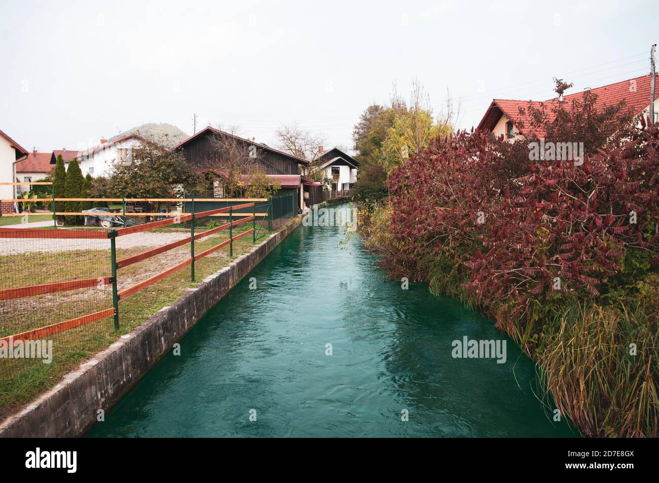 Der kleine Fluss geht in das Dorf zwischen den Häusern, die Herbstsaison. Stockfoto