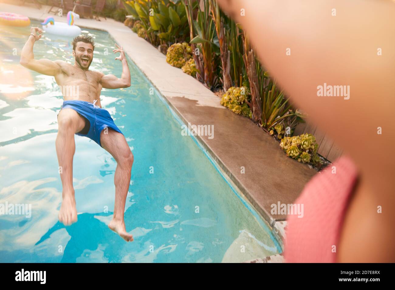 Hispanische Paar Mit Frau Schieben Mann In Schwimmbad An Sommerfest Im Freien Stockfoto