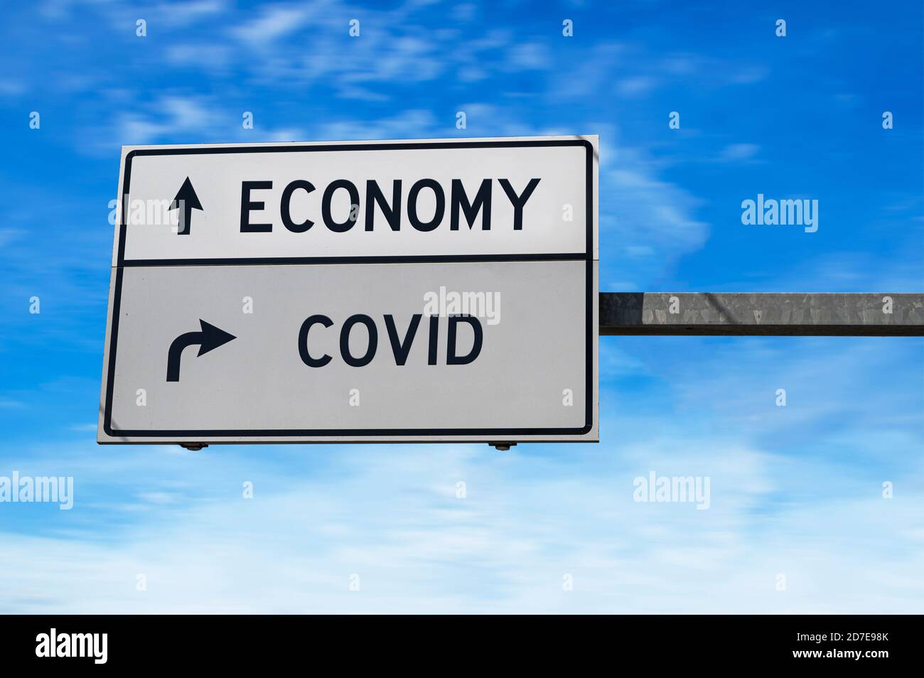 Economy im Vergleich zu COVID. Weiße zwei Straßenschilder mit Pfeil auf Metallmast. Richtungsstraße. Kreuzung Straßenschild, Zwei Pfeil. Blauer Himmel Hintergrund. Stockfoto