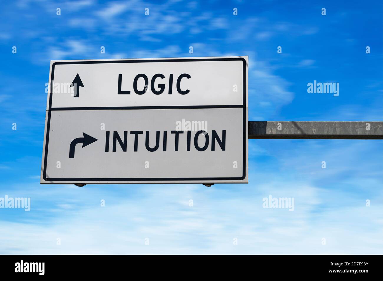 Logik versus Intuition. Weiße zwei Straßenschilder mit Pfeil auf Metallmast. Richtungsstraße. Kreuzung Straßenschild, Zwei Pfeil. Blauer Himmel Hintergrund. Stockfoto