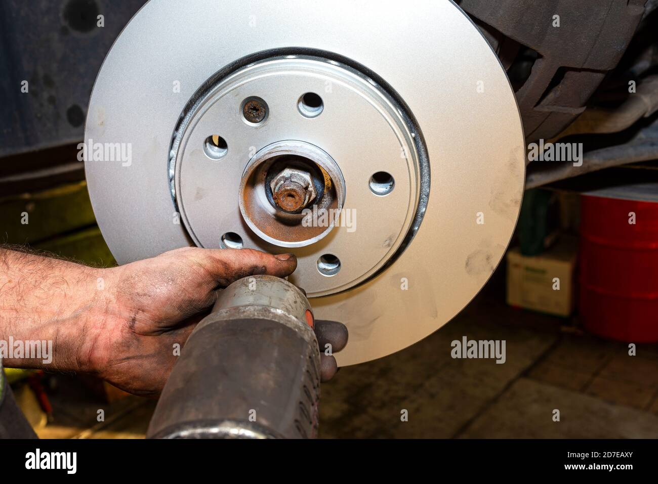 Neue Bremsscheibe mit Korrosionsschutzschicht, montiert an der Vorderradnabe, Schrauben Sie die Bremsscheibe mit einem pneumatischen Schraubendreher. Stockfoto