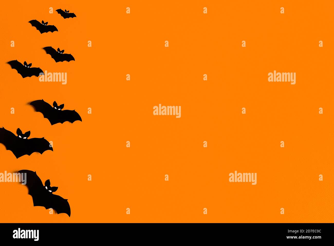 Oranger Hintergrund mit einer Schar von schwarzen Papier Fledermäuse für Halloween, schwarze Papier Fledermaus Silhouetten auf einem orangen Hintergrund, Halloween-Konzept, Copyspace Stockfoto