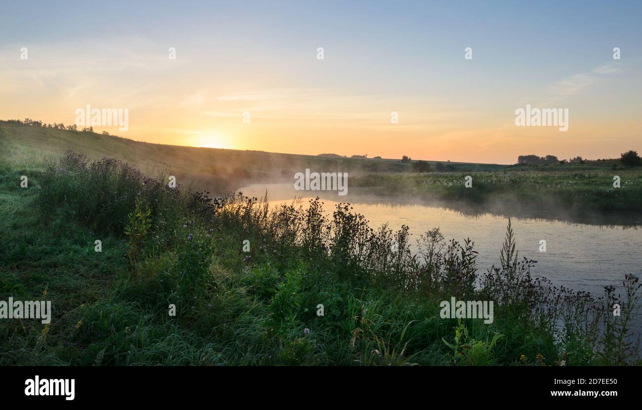 Ruhige, neblige Sommerlandschaft mit Flusskurve und Wiesen. Stockfoto